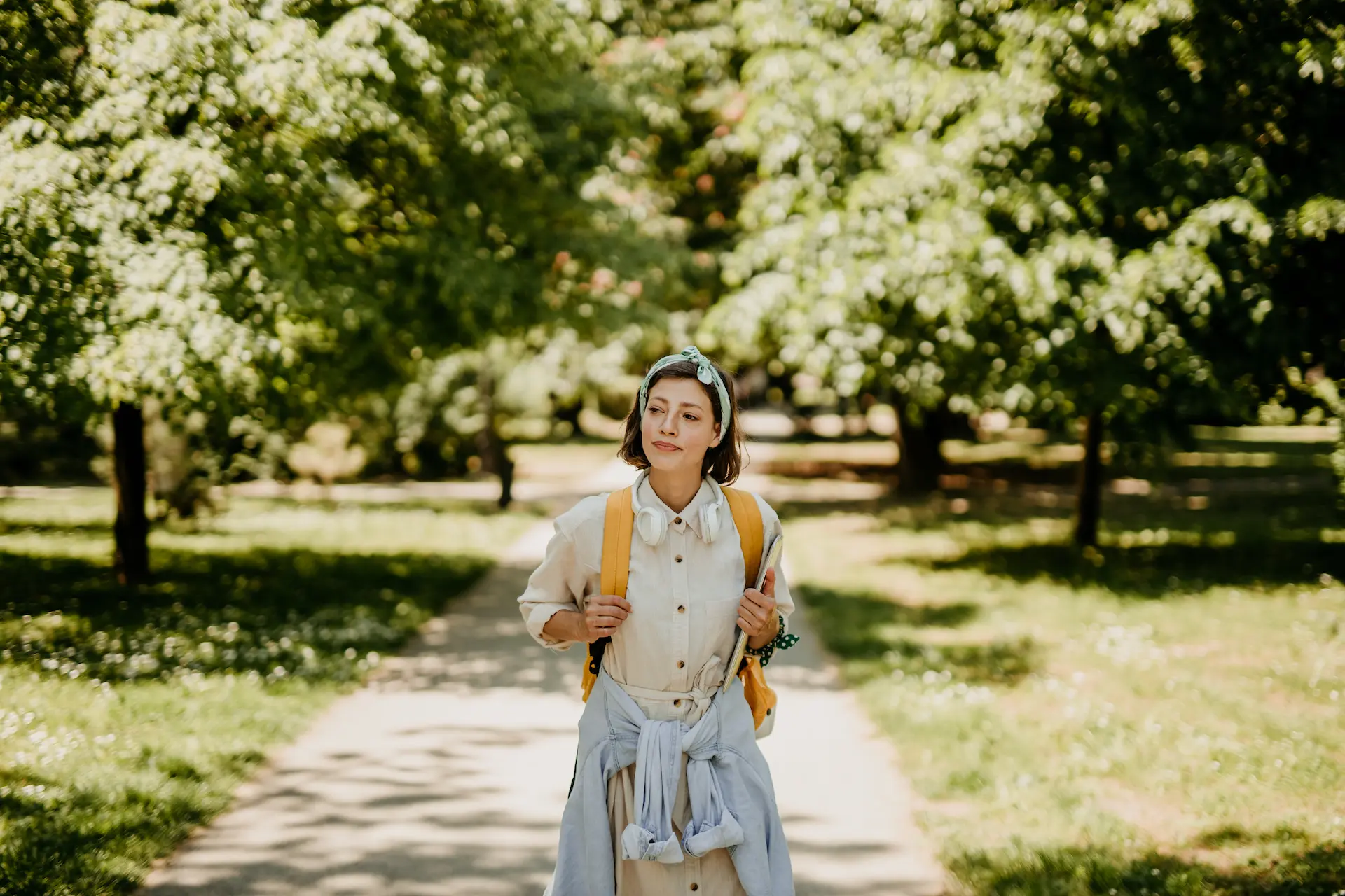 woman with backpack strolling through a park